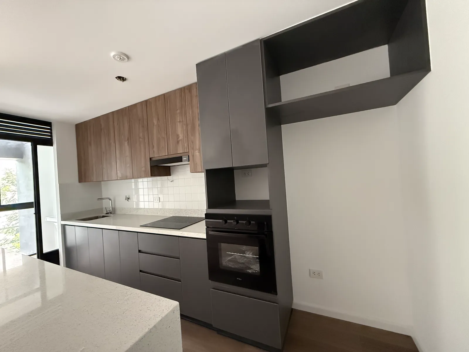 Cocina con muebles altos de melamine y torre de horno del proyecto Porta 360
